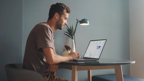 Young Man Using Laptop, Looking at Screen with Business Diagrams and Analytics Stock Footage 120364618