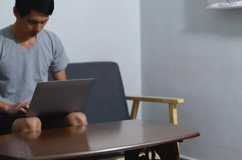 Young Man Using Laptop in Modern Living Room with Simple Furniture Stock Photos