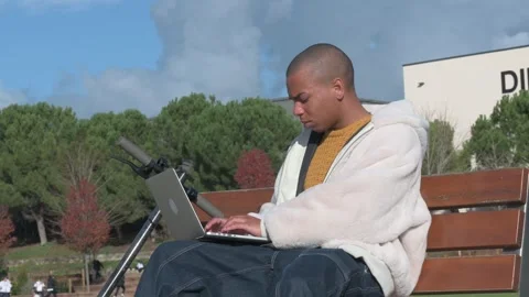 Young man using laptop outdoors, combining work and urban mobility Stock Footage 300260283