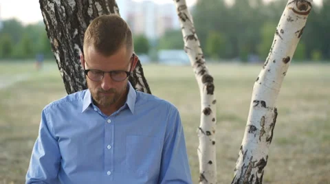 Young man using laptop in the park on a summers day Stock Footage 68077272