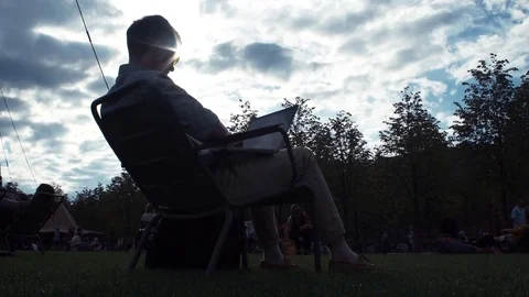 Young man using laptop sitting on chair at city park. Summer day Stock Footage 79356600