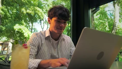 Young man using laptop sitting in restaurant.Businessman Works remotely in t Stock Footage 202479703