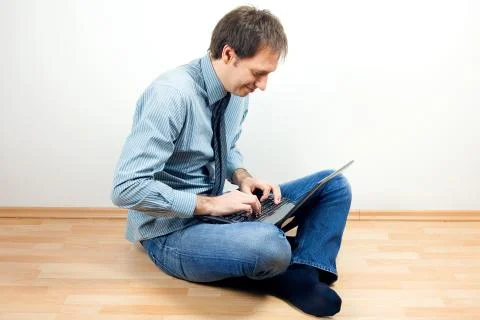 Young man using laptop sitting on the floor in the room Stock Photos