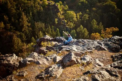 Young man using laptop sitting on a rock slope Foto stock