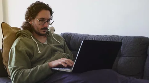 Young man using laptop on the sofa Stock Footage 164905789