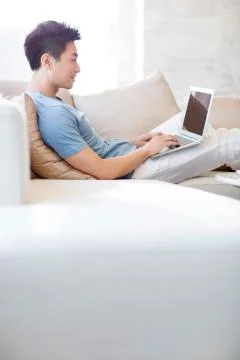 Young man using laptop on the sofa Stock-Fotos