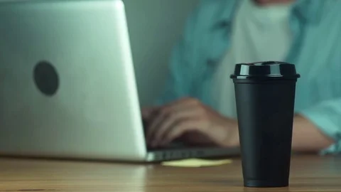 Young man using laptop typing message. Man takes a black hot mug Video stock 81882376