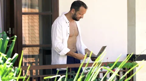 Young man using laptop while standing on terrace with garden view, 120fps Stock Footage 68423094