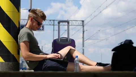 Young man using laptop while waiting for train arrival Video stock 78651021