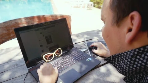 Young man using laptop while relaxing in exotic garden. slow motion. 1920x1080 Stock Footage 88346248