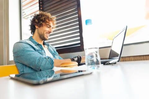 Young man using laptop while to have lunch. Stock Photos