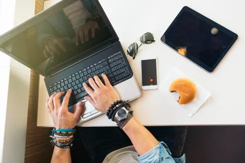Young man using laptop while to have lunch. Stock Photos