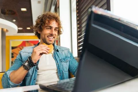 Young man using laptop while to have lunch. Stock Photos