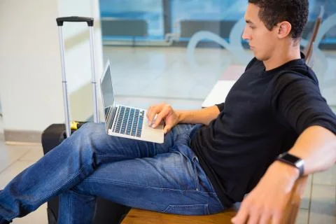 Young Man Using Laptop While Waiting For Flight 写真素材