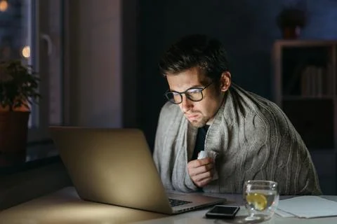 Young man using laptop while suffering from cold Stock Photos