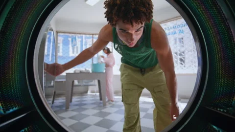 Young man using laundry machine closeup. Self service visitor loading coloured Video stock 247769376