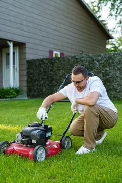 Young man using lawn mower outdoor and checking oil Foto stock