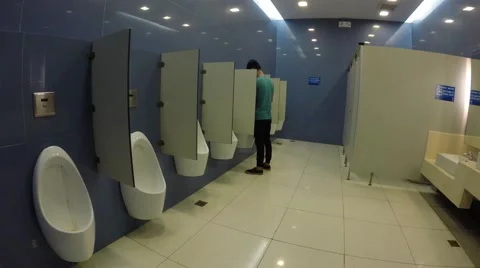 Young man using mall public urinal Stock Footage