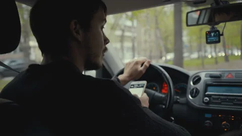 Young man using map app on his smartphone in a car. Footage young man behind the Stock Footage 89818193
