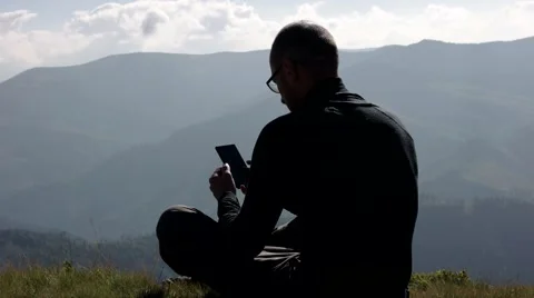 Young Man Using a Mobile Phone on a Mountain Top With Landscape Background Vídeo Stock 65420152