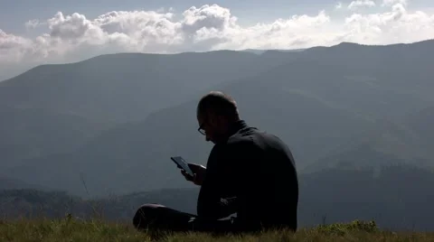 Young Man Using a Mobile Phone on a Mountain Top With Landscape Background Vídeo Stock 65420241