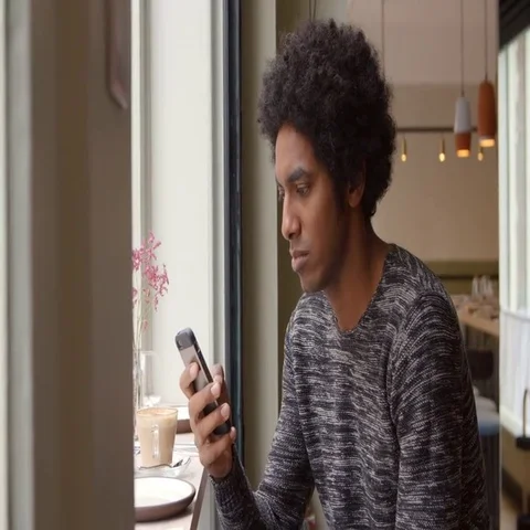 Young Man Using Mobile Phone To Update Social Media In Cafe Stock Footage 69388126