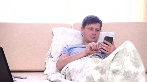 Young man using mobile phone in bed at home Stock Footage 69867394