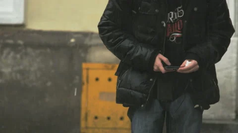 Young Man Using a Mobile Phone in Heavy Rain Stock Footage 88146814