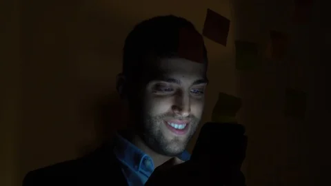 Young man using mobile phone at night in dark office Stock Footage 88558571