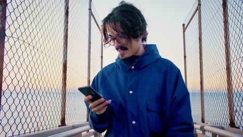 Young man using mobile phone or smartphone app checking social network news feed Stock Footage 100864009