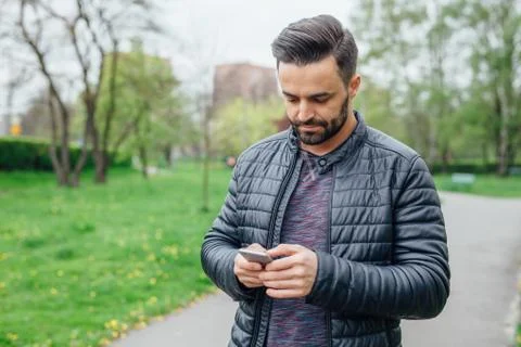 Young man using mobile phone in the park. Stock Photos