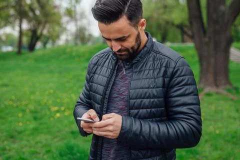 Young man using mobile phone in the park. Stock Photos