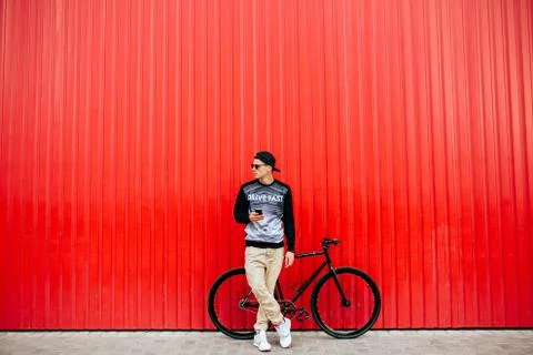 Young man using a mobile phone, standing near the bike, outdoors Stock Photos