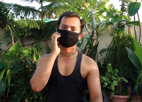 Young man using mobile phone with wear protective mask on face Stock Photos