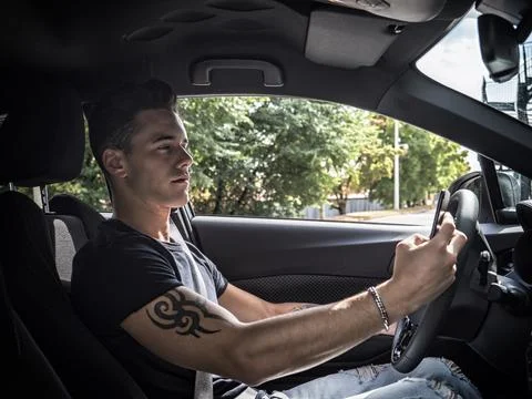 Young man using mobile phone while driving Stock Photos