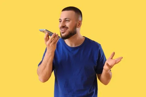 Young man using mobile phone on yellow background. Search concept Foto stock