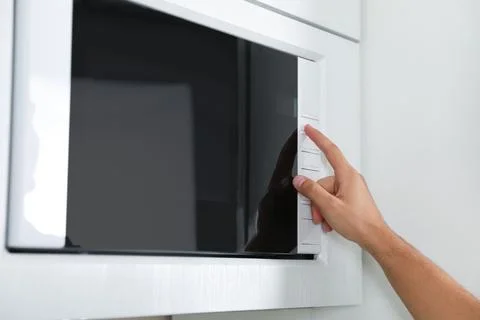 Young man using modern microwave oven, closeup Stock Photos