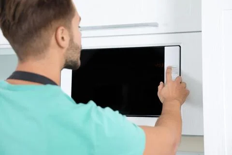 Young man using modern microwave oven at home Stock Photos