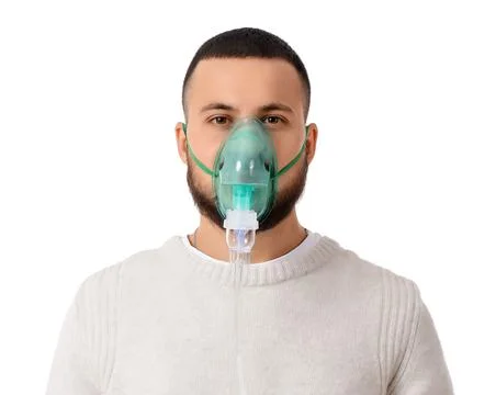 Young man using nebulizer on white background Stock Photos