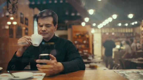 Young man using phone and having coffee in a cafe Video stock 39808217