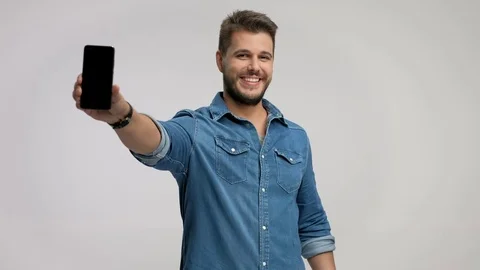 Young man using a phone and showing it to the camera Stock Footage 77297895