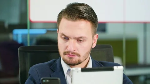 Young Man Using a Phone and a Tablet in the Office Stock Footage 84783747