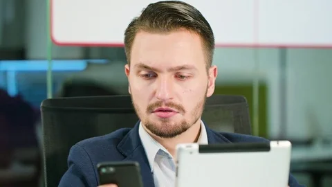 Young Man Using a Phone and a Tablet in the Office Stock Footage 84783887