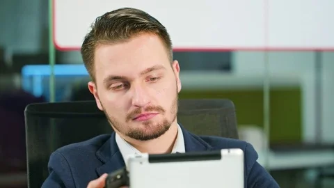 Young Man Using a Phone and a Tablet in the Office Stock Footage 84784332