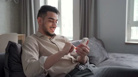 Young man using phone and internet technology sitting on sofa rest at home Stock Footage 169565662