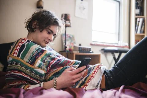 Young man using phone on bed Stock Photos