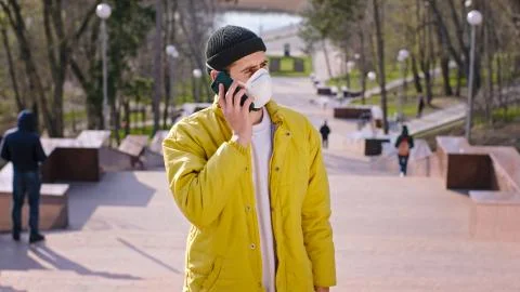 Young man using a phone to make a call while wearing a protective mask on this Stock Photos