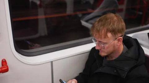 Young man using phone on metro train Stock Footage 342047471