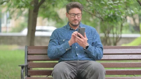 Young Man Using Phone Outdoor on Bench Stock-Footage 311368400