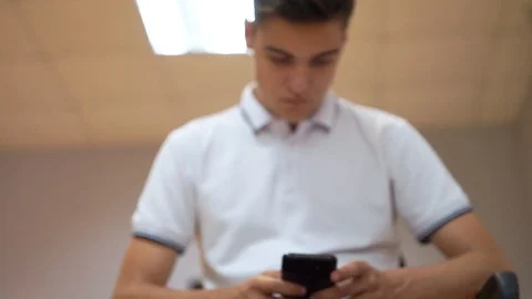 A young man is using the phone for texting or playing games Stock Footage 107671120
